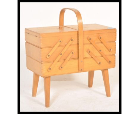 A vintage retro 20th Century teak wood cantilever sewing box having metamorphic action raised on shaped angular legs. Measure