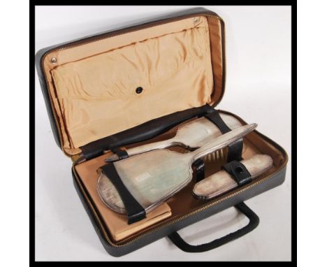 An early 20th Century hallmarked silver three piece travelling vanity set consisting of brushes and mirror. Each piece having