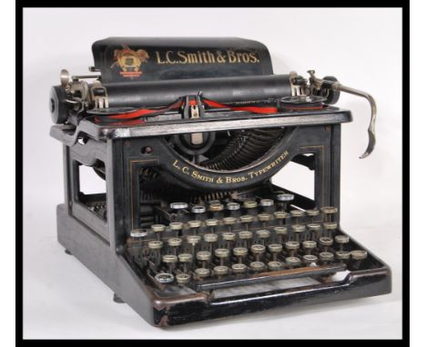 A vintage retro early 20th Century industrial desk top typewriter having large name plaque for LC Smith and Bros. Complete wi