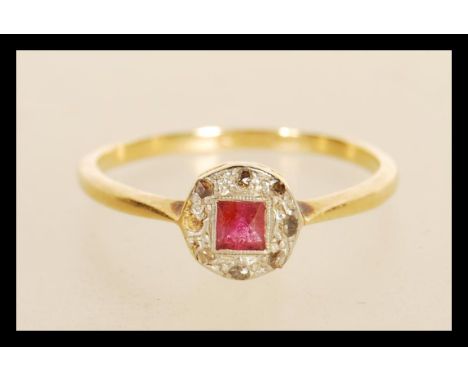 A stamped 18ct gold ring having a round platinum head set with a square cut ruby surrounded by rose cut diamond accent stones