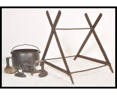 A vintage early 20th Century cast iron saw horse base together with a cast iron cooking pot and other cast items.