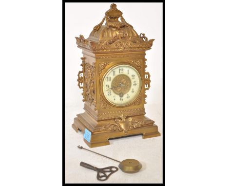 A 19th Century Victorian gilt brass mantel clock raised on a bracket base with armorial decoration and maiden face masks to t