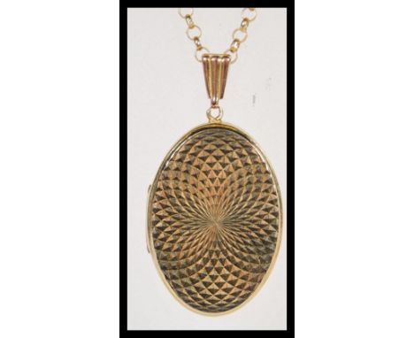 A 9ct gold oval shaped hallmarked locket with engine turned decoration being set to a 9ct gold hallmarked necklace chain. Len