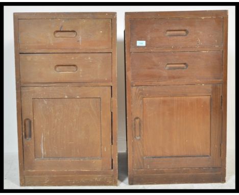 A pair of vintage 20th Century military bedside locker cabinets having a configuration of two drawers with inset handles over