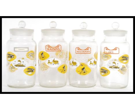 A group of four vintage retro 20th Century glass kitchen storage jars complete with stoppers having printed decoration depict