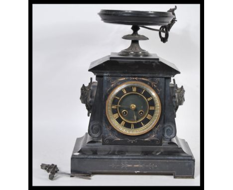 A late 19th century black slate cased mantel clock, of architectural form, the whole surmounted by an urn, having enamelled d