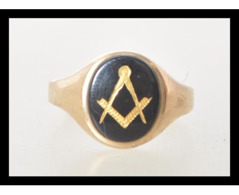 A hallmarked 9ct gold ring set with a oval onyx panel with a gilt masons symbol. Hallmarked London 1965. Weight 2.3g. Size Q.