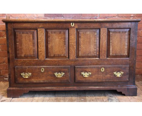 A George III oak and mahogany cross banded mule chest, the hinged cover opening to a fitted candle box, above the four fielde