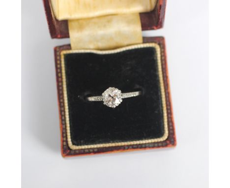 An Art Deco diamond solitaire ring, the central old cut diamond within white metal claw setting edge, leading to diamond set 
