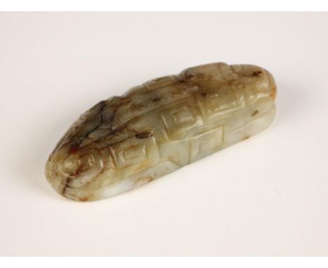 A Chinese carved jade toggle, Ming Dynasty, modelled as a recumbent beast, with geometric motifs, with hues of green, grey an