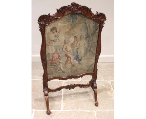 A 19th century French carved walnut fire screen, the swept leaf and 'C' scroll frame enclosing a glazed and shaped needlework