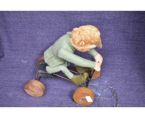 A early Steiff pull along and felt covered Boy wearing green jacket and pixie boots on metal cart with wooden wheels having w
