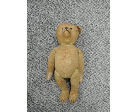 An early/mid 20th century straw filled Steiff style hump back yellow mohair jointed Teddy Bear having replacement plastic eye