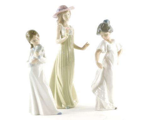 Three Nao porcelain figurines, one holding a pink flower, one a puppy and a girl holding her dress. (3)