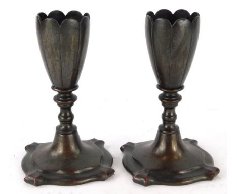 A pair of bronze petalled candle stands, each with a ribbed top on shaped square base 13cm high.