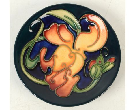 A Moorcroft pottery `Snapdragon` pattern coaster, shape 780, by Emma Bossons, indistinct green painted initials `UBE`and blac