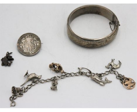 A post-war silver bangle, a silver articulated crocodile pendant, a silver charm bracelet and a silver coin brooch.