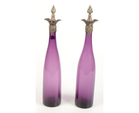 A pair of amethyst glass wine bottles with silver tops decorated with vine leaves. 