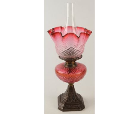 A late Victorian cast iron and cranberry glass oil lamp, height 52.5cm. Condition report: The font is cracked all around.  Sh