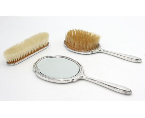 A silver mounted engine turned dressing table mirror and two matching brushes.