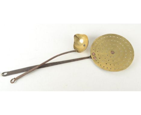 An 18th century brass cream skimmer, with iron handle, length 65cm, diameter 21cm and a brass ladle.