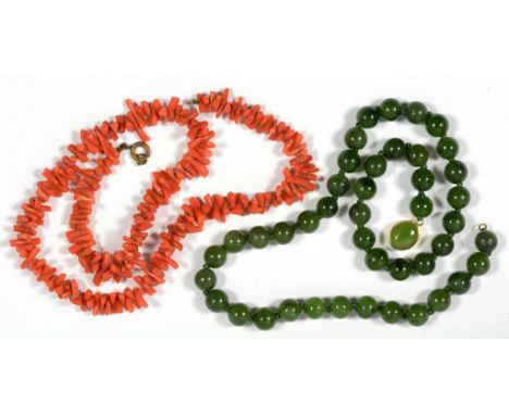 A NECKLACE OF NEPHRITE BEADS WITH GOLD CLASP AND A CORAL NECKLACE