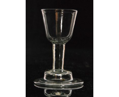 An 18th Century drinking glass circa 1730, round funnel bowl above a short plain stem, raised to a helmet domed and folded fo