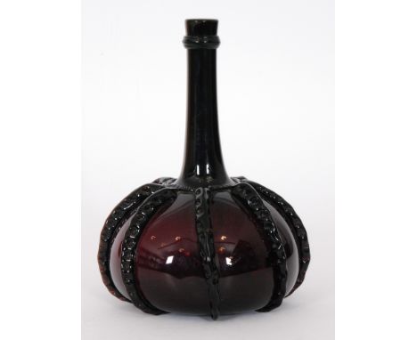 An 18th Century amethyst glass flask of compressed globe and shaft form with tall slender neck, decorated with applied self c