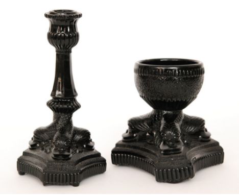 A late 19th Century black pressed glass candlestick attributed to Davidson the triform base formed with the fish heads rising
