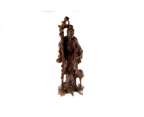 A vintage Chinese root carving of a figure, the male figure with long walking stick, holding vegetation while standing next t