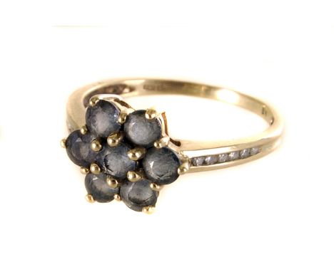 A 9ct gold green sapphire and diamond cluster ring, the seven round cut sapphires forming a floral cluster, flanked by small 