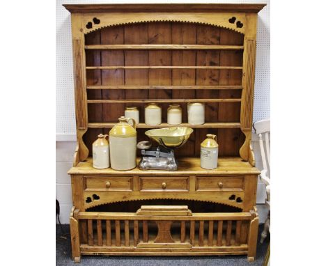 A pine farmhouse dresser, three shelves to top, three short drawers over recess with lifting barred gate