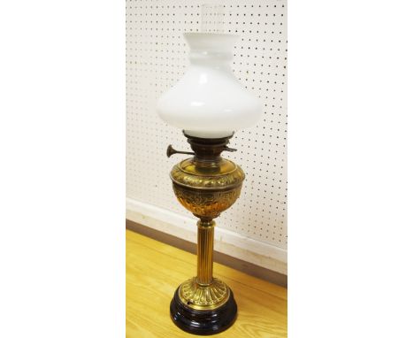 A brass oil lamp, embossed reservoir, opaque shade, circa 1900