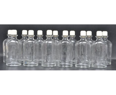 A collection of thirteen vintage mid 20th century circa 1950s Art Deco style Harrods bottles having reeded sides with cream s
