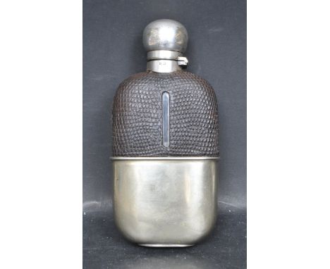 An early 20th century circa 1920 white metal hip flask having a hinged stopper with leather case and shot cup to the base. St