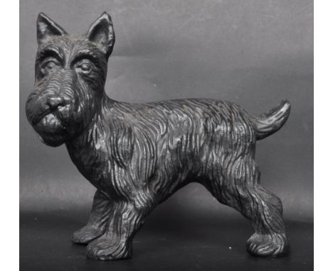 A vintage style cast metal door stop in the form of a Scottish Terrier cocking its leg having textured detailing throughout. 