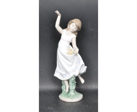 A ceramic porcelain Spanish Lladro Event 1999 hand painted figurine entitled 'Garden Dance' depicting a young girl dancing wi