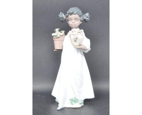 A ceramic porcelain Spanish Lladro figurine entitled 'First Flowers' depicting a young girl holding two flower pots. Figure m