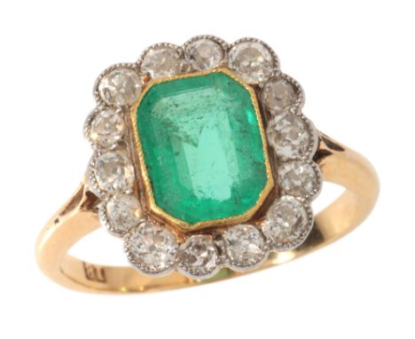 AN ANTIQUE EMERALD AND DIAMOND CLUSTER RINGin 18ct gold and platinum, set with a step cut emerald of c.1.45 carats, surrounde