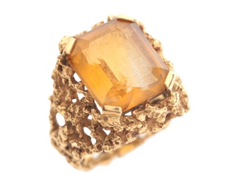 A MODERNIST CITRINE RINGin 18ct gold, set with a step cut citrine of c.8.23 carats, held in a four-claw setting to a textured