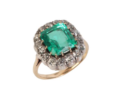 A FINE COLOMBIAN EMERALD AND DIAMOND CLUSTER RINGin 18ct gold and silver, set with an octagonal mixed cut emerald of 3.78 car