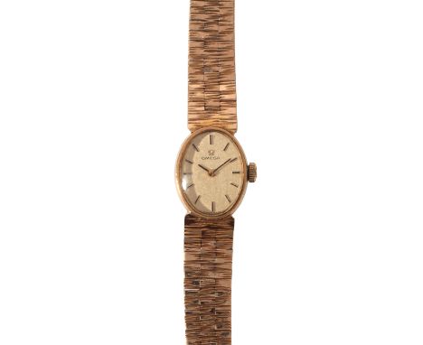 OMEGA: A LADY'S 9CT GOLD BRACELET WATCHwith manual wind movement, the oval gold dial with dark blue and gold baton numerals a