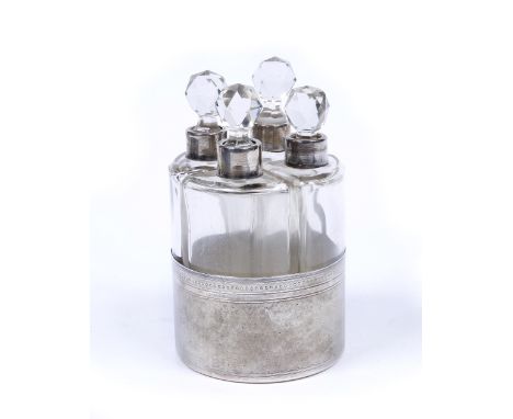 A set of four glass bottles forming the quadrants of a circle, in white metal slip with engine turned decoration and further 