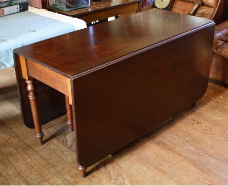 An early 19th century mahogany drop-leaf cottage dining table, with double gate-leg supports, raised on turned legs with toup