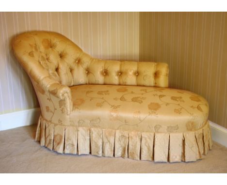 A Victorian button back chaise longue, on turned ebonised legs beneath a pleated valance, re-upholstered in gold floral damas