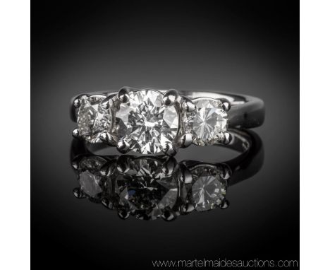 An 18ct white gold and diamond three stone ring, the central brilliant cut diamond flanked by a pair of smaller brilliant cut