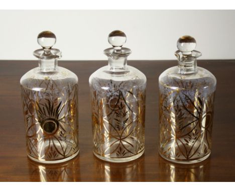 A set of three Continental glass decanters, 19th century, circular with foliate gilded line decoration, pouring lips to the r