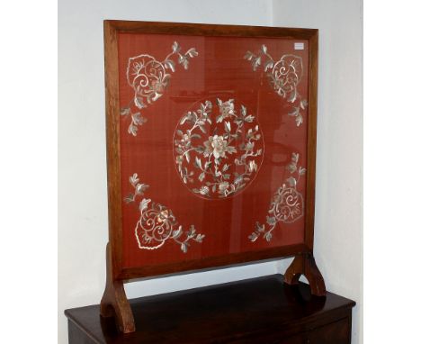 A Chinese embroidered silk fire-screen, early 20th century, in a stained beech frame, the central circular motif of flowers i