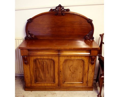 A Victorian mahogany chiffonier, with raised semi-circular back with moulded and carved surround, the plain top over two shap