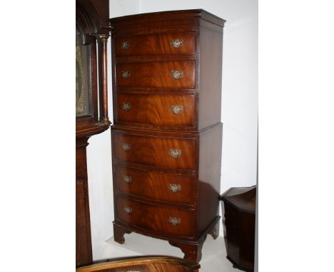 A reproduction mahogany veneered miniature bow front chest on chest, the top section with three graduated drawers over the ba